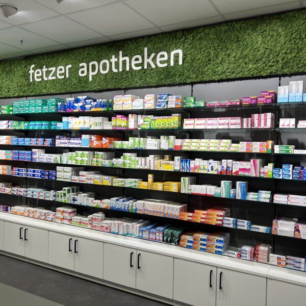 Fetzer Apotheke: Tegometall-Apothekenrückwand mit Firmenlogo auf konserviertem Moos